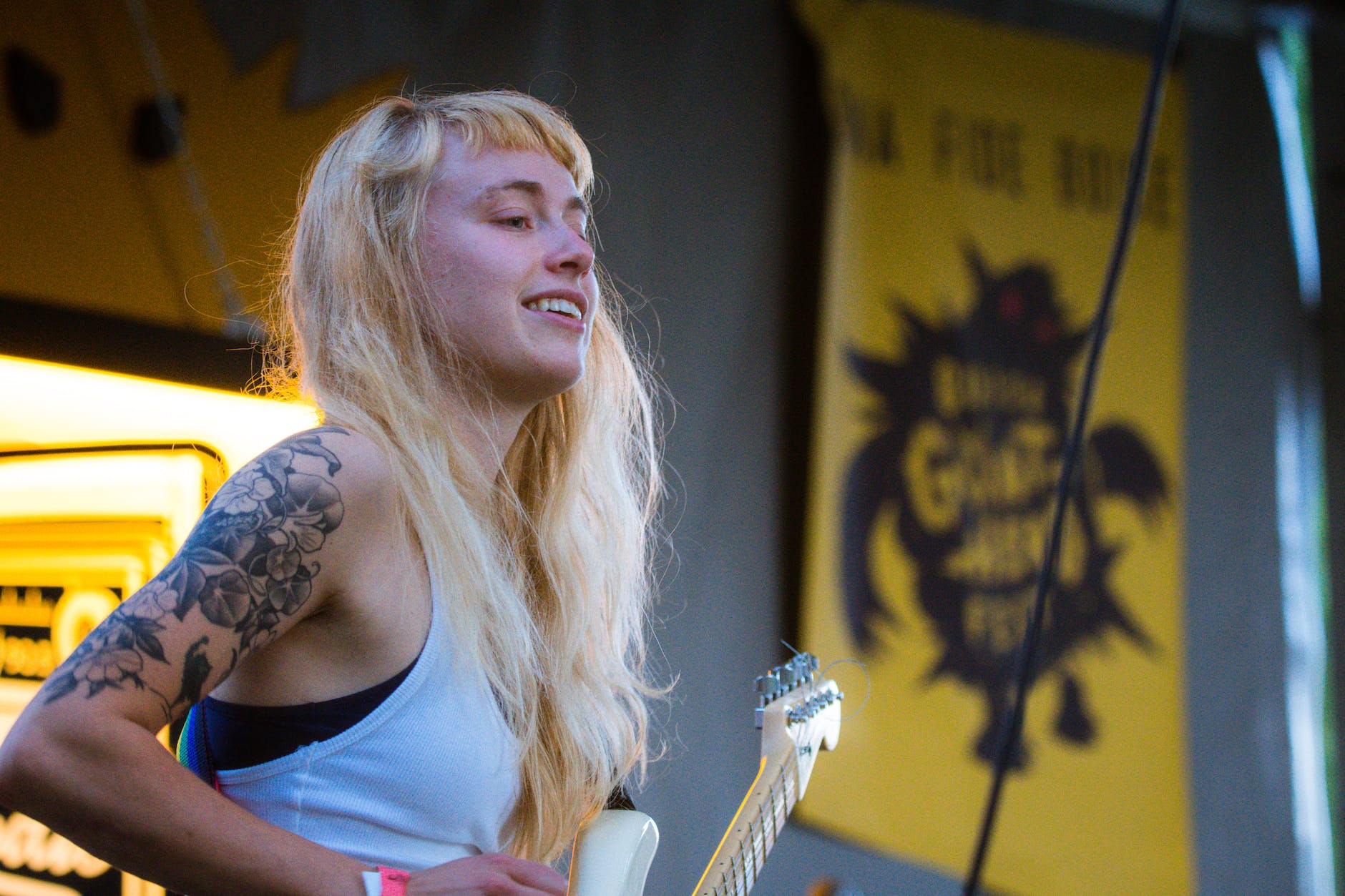 woman wearing white tank top playing white electric guitar