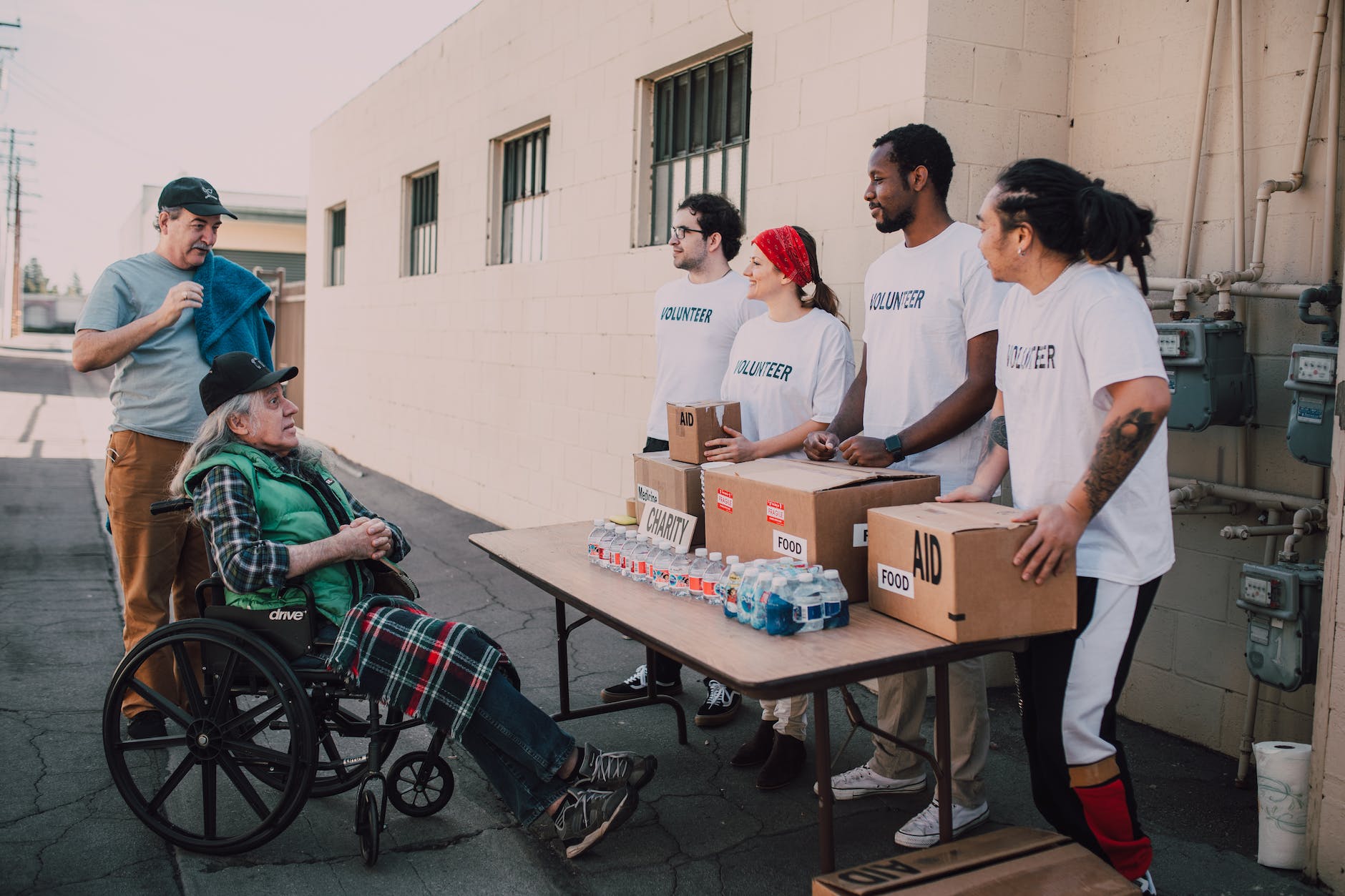 volunteers assisting an old man on a wheelchair