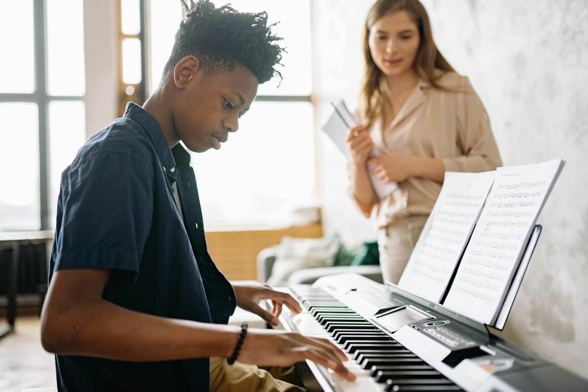 kid playing a piano beside a woman